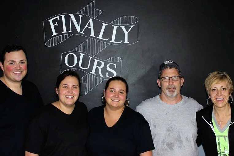 The Finally Ours family in front of our chalkboard sign